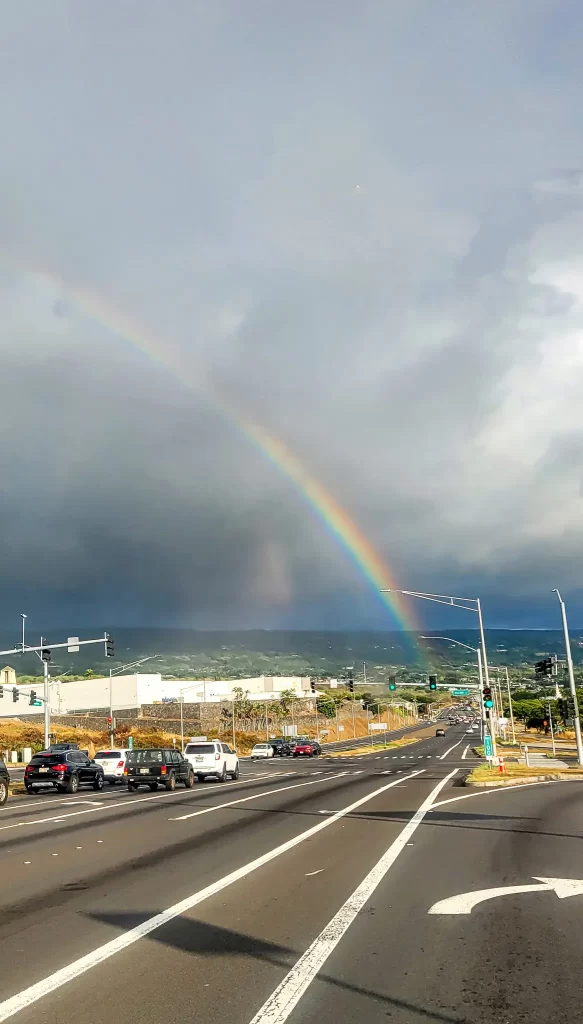 A huge rainbow stretches across a road near the Hawai'i airport.