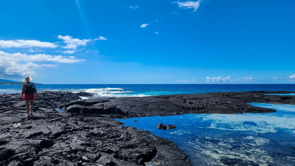 Elyse walking on the basalt jetty towards the blue Pacific Ocean.