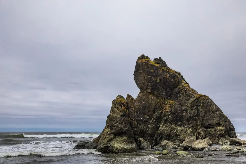 A jagged dark rock, erupted from the otherwise smooth beach.