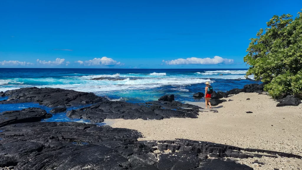 Elyse walking on the sand towards the blue Pacific Ocean.