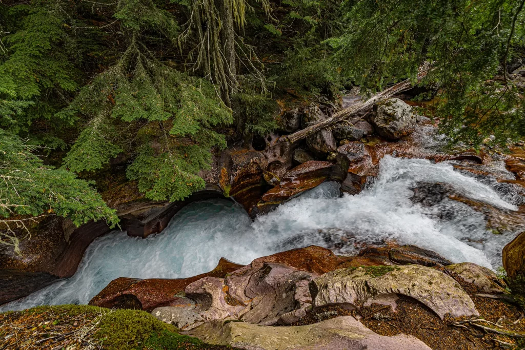 Water funnels through the smooth red rock of Avalanche Creek.