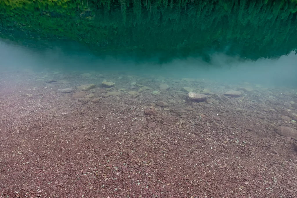 Bluegreen water fades to red rocky shoreline.