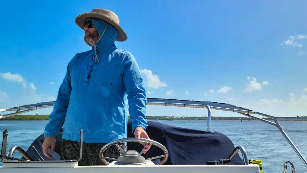 Tom standing up from the helm, looking over he side of the yacht.