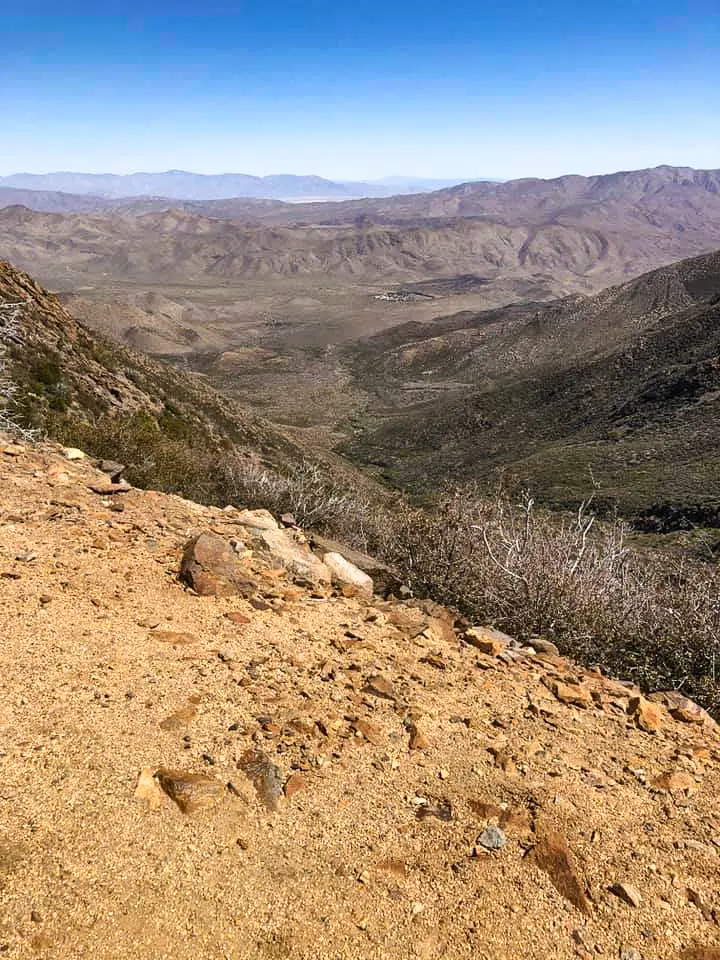 Rocky dirt trail leads off into rolling hills.