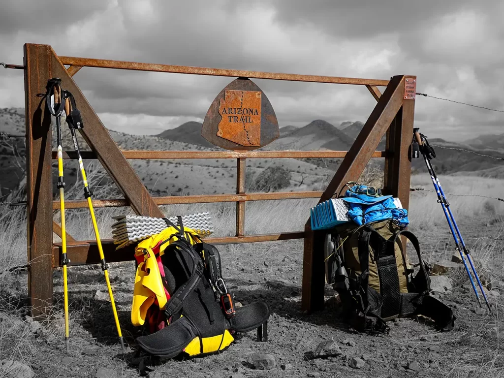 Two backpacking bags propped on an Arizona Trail gate near Vail, Arizona.